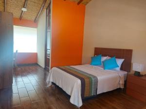 1 dormitorio con 1 cama con pared de color naranja en La Finka Cajamarca en Cajamarca