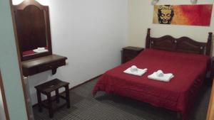 a bedroom with a red bed with two white shoes on it at Hotel OLLANTAY- BV Hoteles in La Falda