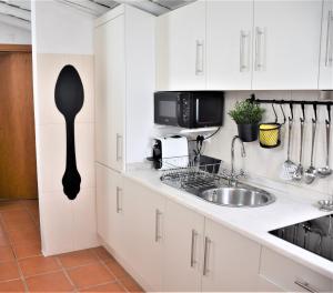 a kitchen with white cabinets and a sink at Casa da Chaminé - Refúgio com Charme Alentejano in Amieira +22 photos