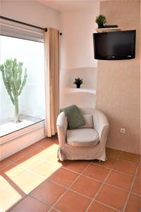 a living room with a chair and a flat screen tv at Casa da Chaminé - Refúgio com Charme Alentejano in Amieira