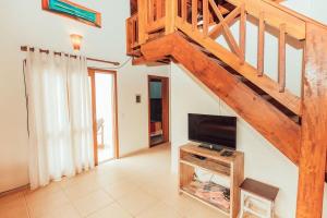 a living room with a tv and a staircase at Acomodações Ibirawave in Barra de Ibiraquera