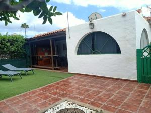 a backyard with a white building with a green gate at Bungalow en el sur de Gran Canaria in Las Palmas de Gran Canaria