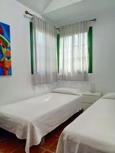 two beds in a room with white walls at Bungalow en el sur de Gran Canaria in Las Palmas de Gran Canaria