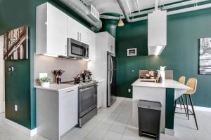 a kitchen with green walls and white cabinets at NYC Styled Loft In DTLA, sleeps 4 with Free Parking! in Los Angeles