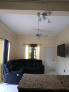 a living room with a black couch and a tv at Ark Royal of the Caribbean in Arnos Vale