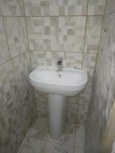La salle de bains carrelée est pourvue d'un lavabo blanc. dans l'établissement Ark Royal of the Caribbean, à Arnos Vale