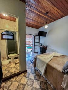 a bedroom with a bed and a view of a bathroom at Suítes O Pinhão e a Mantiqueira in Santo Antônio do Pinhal