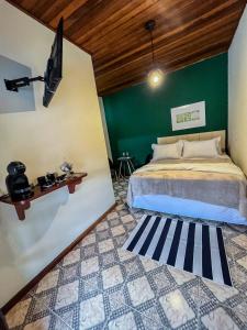 a bedroom with a bed and a green wall at Suítes O Pinhão e a Mantiqueira in Santo Antônio do Pinhal