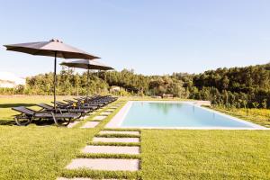 a swimming pool with lounge chairs and an umbrella at A Casa da Quintã - Piscina exterior e interior aquecida in Cabeceiras de Basto