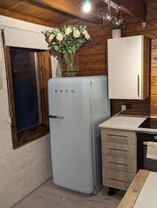 a kitchen with a white refrigerator and a vase of flowers at Gorgeous countryside cabin in Lyminge