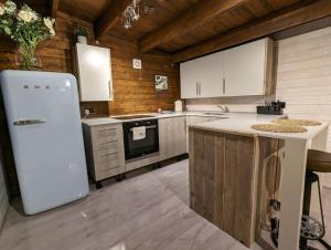 a kitchen with a white refrigerator and wooden walls at Gorgeous countryside cabin in Lyminge