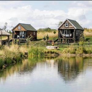 a couple of houses next to a body of water at Lake View Lodges in Long Melford