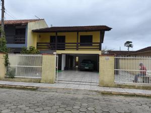 una casa amarilla con una valla blanca y una entrada en Casa Amarela, en Navegantes