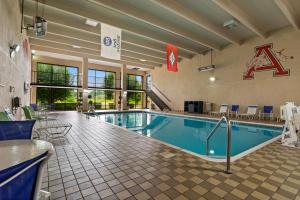 una piscina en una habitación de hotel con sillas y mesa en Best Western Windsor Suites en Fayetteville