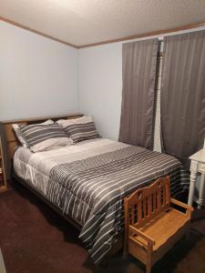 ein Schlafzimmer mit einem Bett und einem Holzstuhl in der Unterkunft Thomas Holiday Home in Clearfield