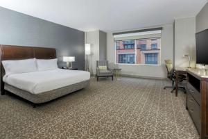 a hotel room with a bed and a desk and a window at Hilton Garden Inn Shirlington in Arlington