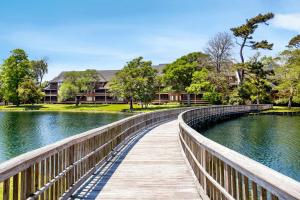 a wooden bridge over a lake with a house in the background at Kingston Plantation Condos in Myrtle Beach
