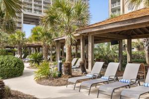 a patio with chairs and palm trees at the resort at Hilton Myrtle Beach Resort in Myrtle Beach