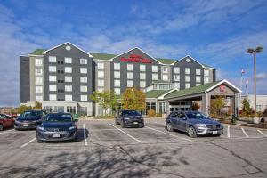 ein großes Hotel mit Autos auf einem Parkplatz in der Unterkunft Hilton Garden Inn Toronto/Ajax in Ajax