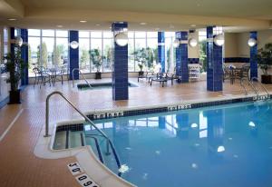 a swimming pool in a hotel with tables and chairs at Hilton Garden Inn Toronto/Ajax in Ajax