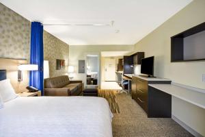 Habitación de hotel con cama extragrande y escritorio. en Home2 Suites By Hilton Oswego, en Oswego