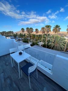 a white table and chairs on a balcony with palm trees at Cactus del Mar in Tarajalejo