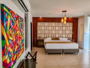- une chambre avec un lit et une peinture murale dans l'établissement Hotel Andinos Plaza Florencia, à Florencia