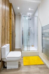 a bathroom with a toilet and a shower and a yellow rug at City Centre Vintage Chic Studio in Manchester