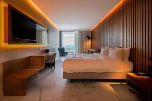 um quarto de hotel com uma cama, uma secretária e uma televisão em Radisson Beach Resort Larnaca em Larnaka