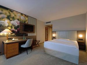 ゲーラにあるMercure Hotel Gera Cityのベッド、デスク、テレビが備わるホテルルームです。