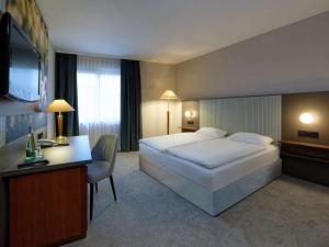 um quarto de hotel com uma cama grande e uma secretária em Mercure Hotel Gera City em Gera