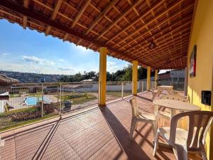 a balcony with a table and chairs and a view at Chacara com piscina, churrasq e WiFi em Taubate SP in Taubaté