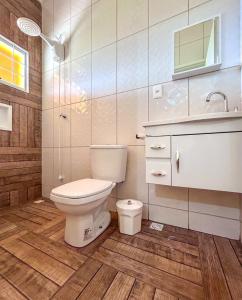 uma casa de banho com um WC, um lavatório e um espelho. em Chacara com piscina, churrasq e WiFi em Taubate SP em Taubaté