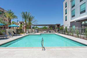 a swimming pool with chairs and a building at Hilton Garden Inn Surprise Phoenix in Surprise