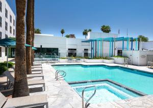 une piscine avec des chaises et un bâtiment dans l'établissement DoubleTree by Hilton Chandler Phoenix, AZ, à Chandler