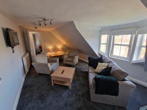 uma sala de estar com um sofá, cadeiras e uma mesa em Teviotside Travel Inn Ltd em Hawick