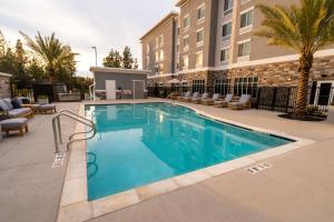 uma piscina num hotel com cadeiras e um edifício em Homewood Suites By Hilton Rancho Cordova, Ca em Rancho Cordova