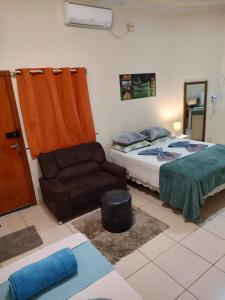 um quarto com uma cama e um sofá em Pousada AM PM em Campo Grande