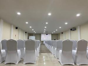 Sala de conferencias con sillas blancas y pantalla de proyección en Illary Hoteles, en Pozo Almonte