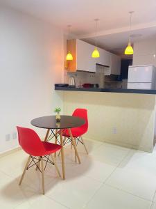 a kitchen with a table and four red chairs at Apto Garagem Wifi Condomínio Piscina Ar-condicionado 2 Quartos in Petrolina