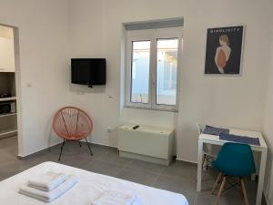 a room with a bed and a desk and a tv at Leo's Apartments in Koropíon