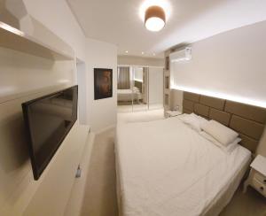 Dormitorio pequeño con cama y TV en Apartamento Residencial Bordô amplo 3 quartos próximo à praia, en Itapema
