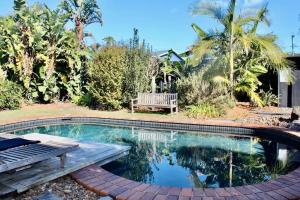 a swimming pool with a wooden bench and a bench at Caba Beach Casa in Cabarita Beach