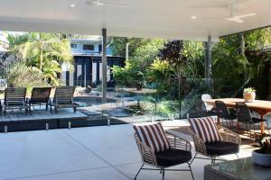 a patio with chairs and a table and an umbrella at Caba Beach Casa in Cabarita Beach