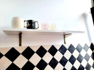 a shelf with cups and glasses on a checkered floor at One bedroom by the Park Old Town Timisoara in Timişoara
