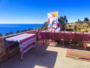Huillanopampa的住宿－Taquile Inti Raymi Lodge，坐在桌子上欣赏海景的人