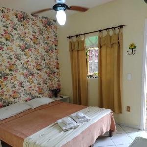 1 dormitorio con 1 cama y papel pintado con motivos florales en Pousada Linda Borboleta, en Conservatória