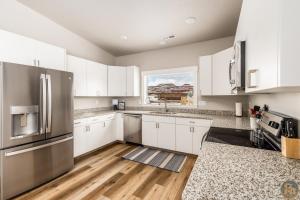 a kitchen with white cabinets and a stainless steel refrigerator at Maynard Dixon: Desert Luxury & Stargazer's Oasis in Kanab