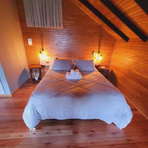 um quarto com uma cama grande e paredes de madeira em Cerro Leão Estância- chalé em Bom Jardim da Serra