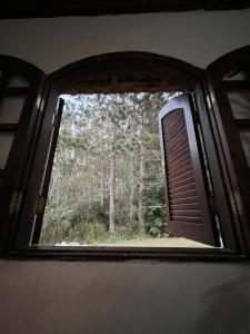 an open window with a view of a forest at Pousada Chalés da Lua in Munhoz
